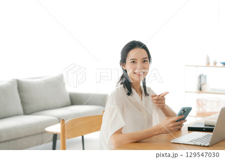 リビングでスマホを持つ女性 リビングでスマホを持つ女性 129547030