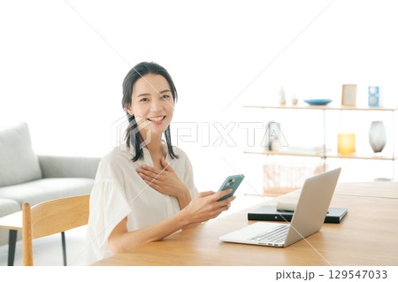 リビングでスマホを持つ女性 129547033