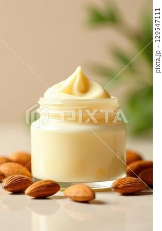 Jar of almond cream surrounded by almonds on reflective surface 129547111