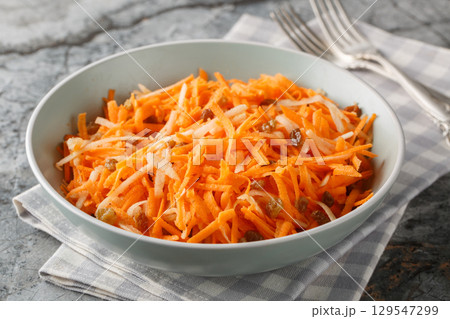 Juicy carrot apple salad with raisins with lemon dressing close-up in a bowl. horizontal Juicy carrot apple salad with raisins with lemon dressing close-up in a bowl. horizontal 129547299