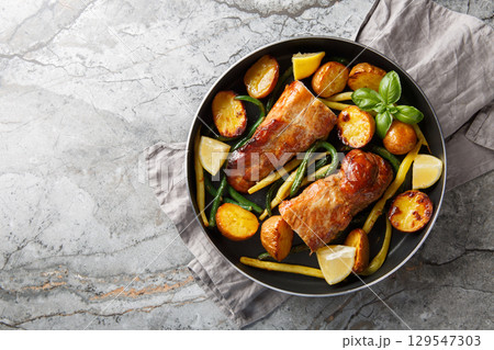 Tender pork tenderloin garlic lemon baked with potatoes and green beans close-up in a frying pan. horizontal top view 129547303