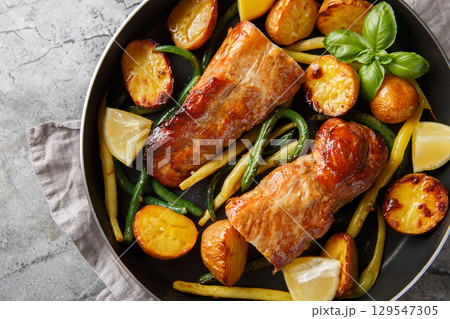 Baked Lemon garlic Pork Tenderloin with french beans and new Potatoes close-up in a pan. Horizontal top view Baked Lemon garlic Pork Tenderloin with french beans and new Potatoes close-up in a pan. Horizontal top view 129547305