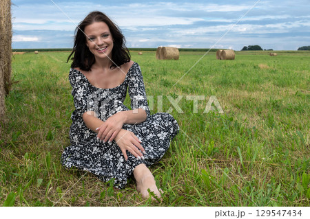 Smiling Woman in a Field with Hay Bales 129547434