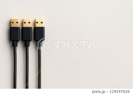 Three black cables with gold connectors are laying on a white surface 129547626