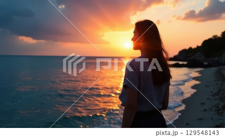 Young Woman in a Flowing White Dress Enjoying a Serene Sunset at the Beach 129548143