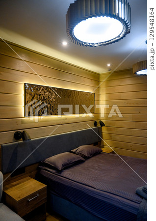 Hotel room with wooden interior, bed and night light 129548164