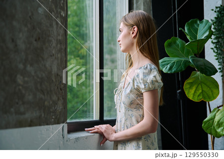 Young beautiful dreaming romantic girl looking out the window 129550330
