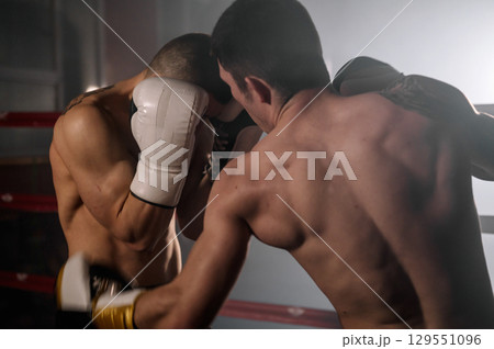 Two professional young muscular shirtless male boxers fighting in a boxing ring. Two professional young muscular shirtless male boxers fighting in a boxing ring. 129551096