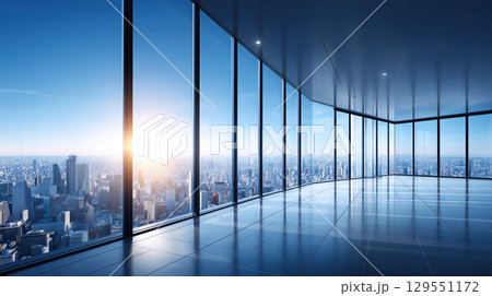 Spacious modern office with large glass windows overlooking a bright sunrise and urban city skyline 129551172