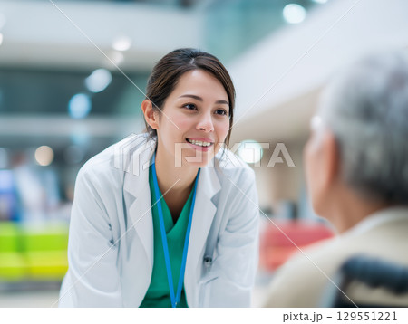 車椅子に座った高齢の患者と笑顔で話す女性医師 129551221