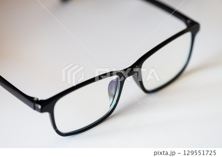 Closeup of modern eyeglasses on white background with shadow Closeup of modern eyeglasses on white background with shadow 129551725