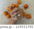 Apricots on gray stone with woman's hand and oval diamond ring 129551795