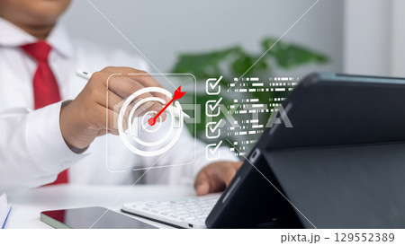 Business strategy, goal setting, marketing objectives, and achieving success in a professional environment.Businessman uses stylus on digital screen with target and goals list. 129552389