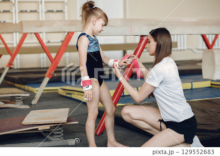 Coach with student. Girls gymnasts, performs various gymnastic exercises and jumping. Childs and sport, a healthy lifestyle. Coach with student. Girls gymnasts, performs various gymnastic exercises and jumping. Childs and sport, a healthy lifestyle. 129552683