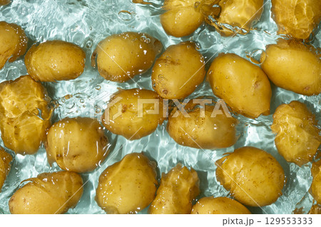 Whole Organic Raw Potatoes In Water Top View, Splash And Ripples. Whole Organic Raw Potatoes In Water Top View, Splash And Ripples. 129553333