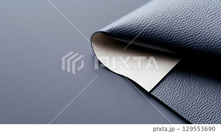 Close up view of a high   luxurious black leather material with a refined sophisticated texture featuring folds creases and contrasting light and shadow details 129553690
