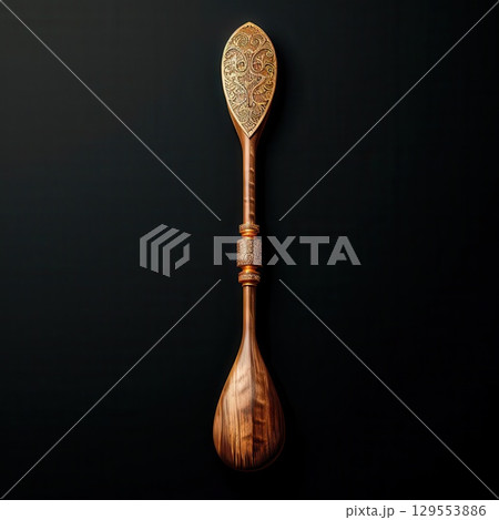 An intricately carved wooden spoon with a unique design, isolated on a black background. An intricately carved wooden spoon with a unique design, isolated on a black background. 129553886