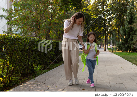 Mother and daughter walking together on a sunny day in the park 129554575