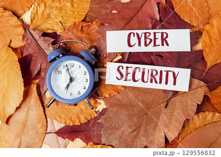 Blue alarm clock is on top of a pile of orange leaves 129556832