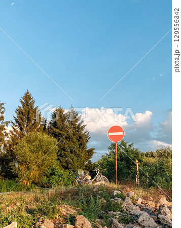 Red and white sign with a white line in the middle is on a hillside 129556842