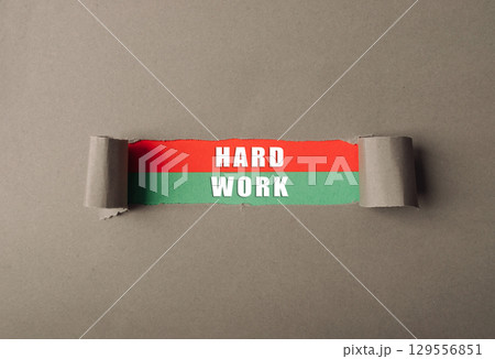 Torn piece of paper with the words hard work written on it 129556851