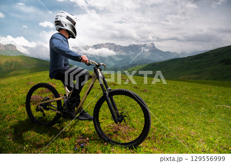 Unrecognizable man with bicycle. Mountain biker stands after riding through summer mountain forest landscape. Outdoor sports 129556999
