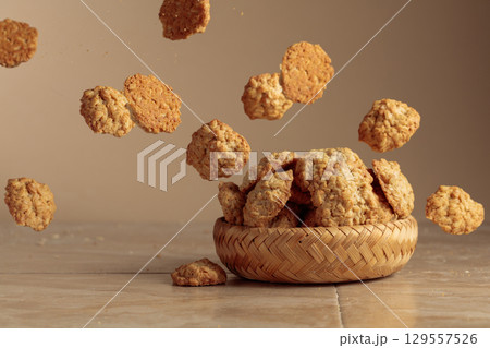 Oatmeal cookies in motion on a beige background. Oatmeal cookies in motion on a beige background. 129557526