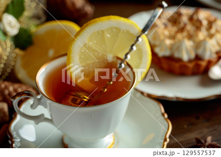 White cup of tea with lemon and meringue tartlet. 129557537