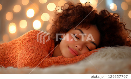 Woman with curly hair sleeping peacefully on fluffy pillow in warm orange sweater. Concept of rest and comfort Woman with curly hair sleeping peacefully on fluffy pillow in warm orange sweater. Concept of rest and comfort 129557797