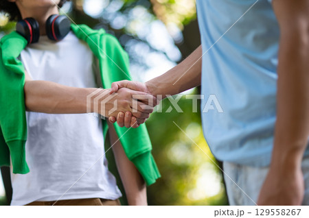 Close up picture of a handshake of two teens in the park 129558267