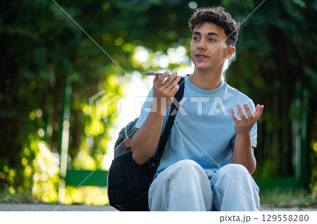 Handsome teen in the park recording a voice message 129558280