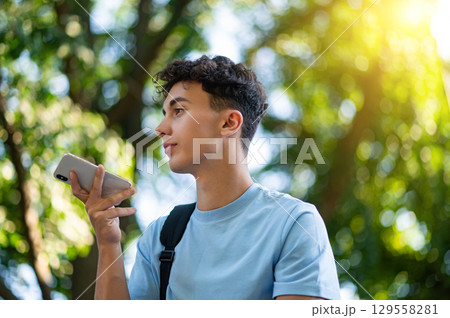Handsome teen in the park recording a voice message 129558281