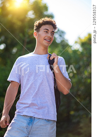Contented teen with a backpack waling in the park 129558317
