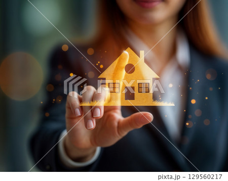 A business professional interacts with a digital house icon, representing real estate innovation in a modern office environment 129560217