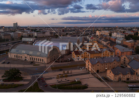 Riga Central Market pavilions and colorful historic buildings under a pink and blue sunset sky with scattered clouds in Riga, Latvia. Riga Central Market pavilions and colorful historic buildings under a pink and blue sunset sky with scattered clouds in Riga, Latvia. 129560882