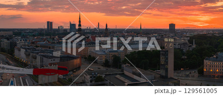 Riga's skyline at sunset features St. Peter's Church, Riga Cathedral, the Daugava River, Vansu Bridge, and modern buildings in the foreground. Riga's skyline at sunset features St. Peter's Church, Riga Cathedral, the Daugava River, Vansu Bridge, and modern buildings in the foreground. 129561005