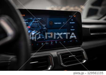 Infotainment screen and dashboard of a Mercedes AMG G Class with carbon fiber accents, dual air vents, and a navigation map in Russian displayed. 129561135