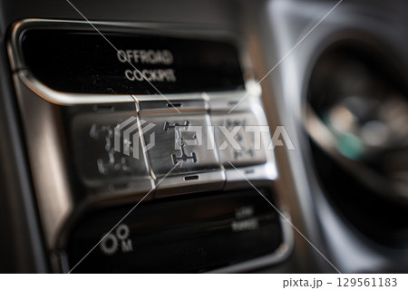 Detailed view of the off road cockpit controls in a Mercedes AMG G Class, featuring metallic buttons for differential lock settings and rugged design. 129561183