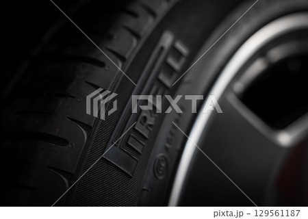 Close up view of a Pirelli tire showing embossed branding, detailed tread pattern, and sleek metallic wheel rim against a blurred background. 129561187