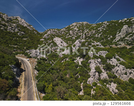 Mountain road across rocky hills of Bozburun peninsula, Turkey under azure sky Mountain road across rocky hills of Bozburun peninsula, Turkey under azure sky 129561608