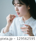 薬をつまんで飲もうとしている日本人女性 129562595