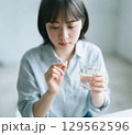 薬をつまんで飲もうとしている日本人女性 129562596