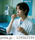 薬をつまんで飲もうとしている医療従事者 129562599