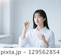 薬をつまんで飲もうとしている日本人女性 129562854