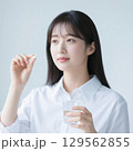 薬をつまんで飲もうとしている日本人女性 129562855