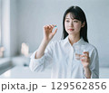 薬をつまんで飲もうとしている日本人女性 129562856