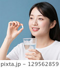 薬をつまんで飲もうとしている日本人女性 129562859