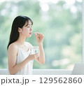 薬をつまんで飲もうとしている日本人女性 129562860