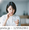 薬をつまんで飲もうとしている日本人女性 129562861