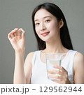薬をつまんで飲もうとしている日本人女性 129562944